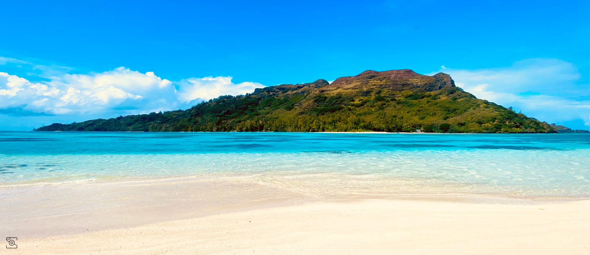Plage de sable blanc en Polynésie française avec vue sur une montagne