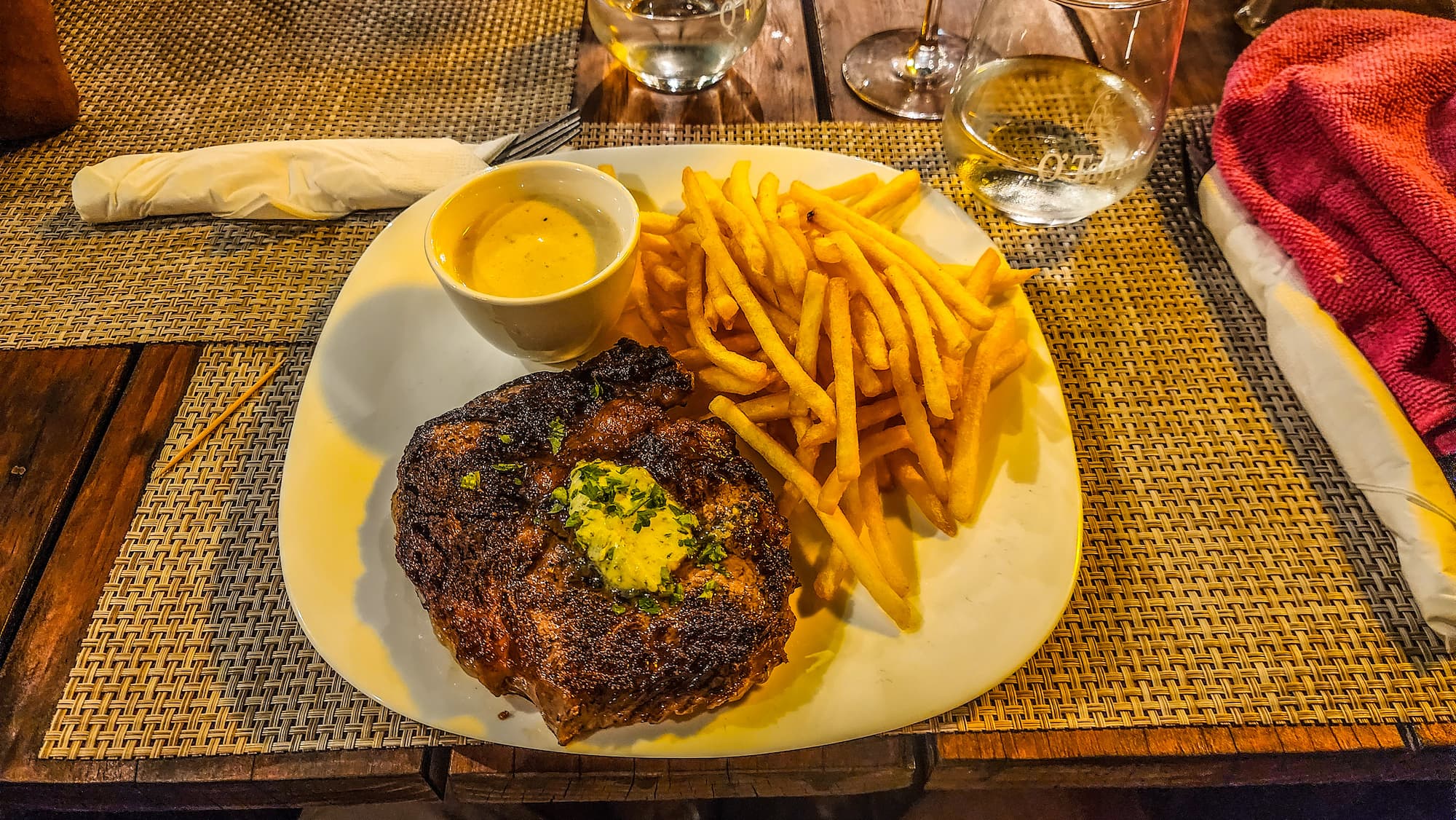 Steak frites servi au Hirinaki Lounge de Fakarava avec sauce et verre de vin rouge