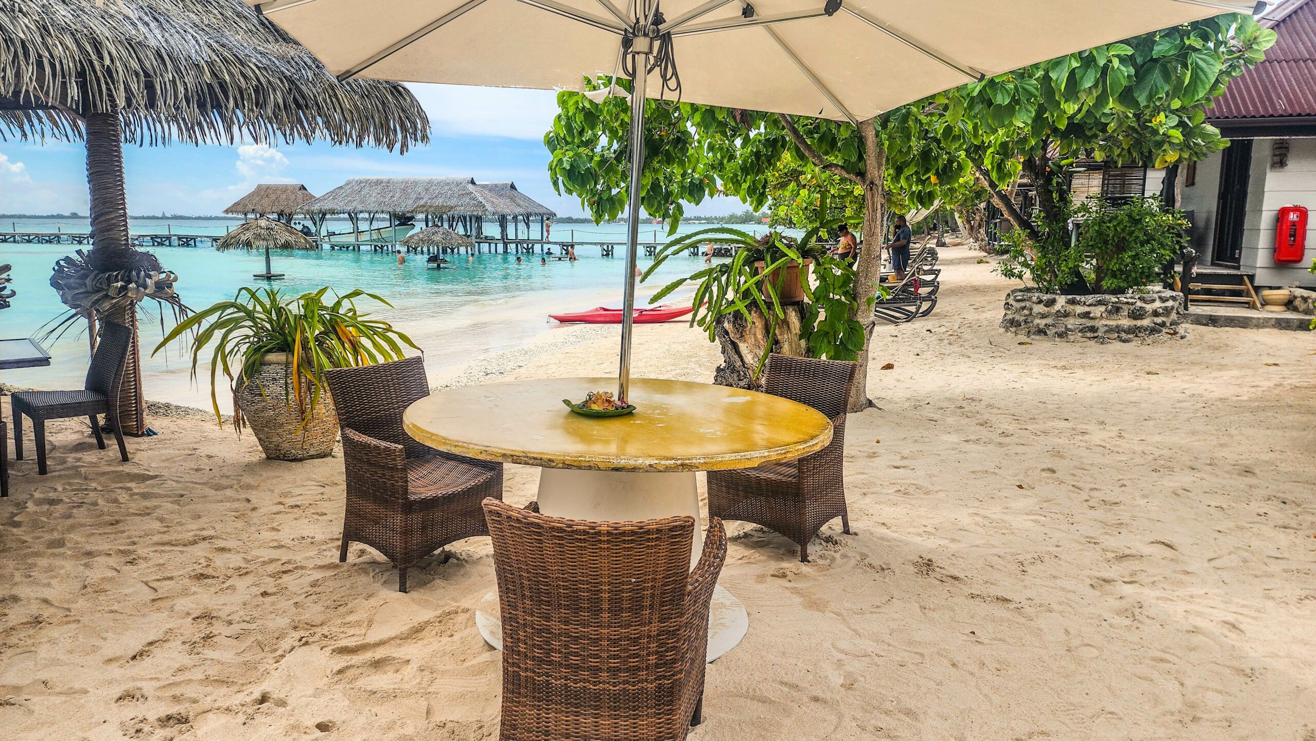 Terrasse du Snack du Requin Dormeur à Fakarava avec tables sous parasols en bord de plage